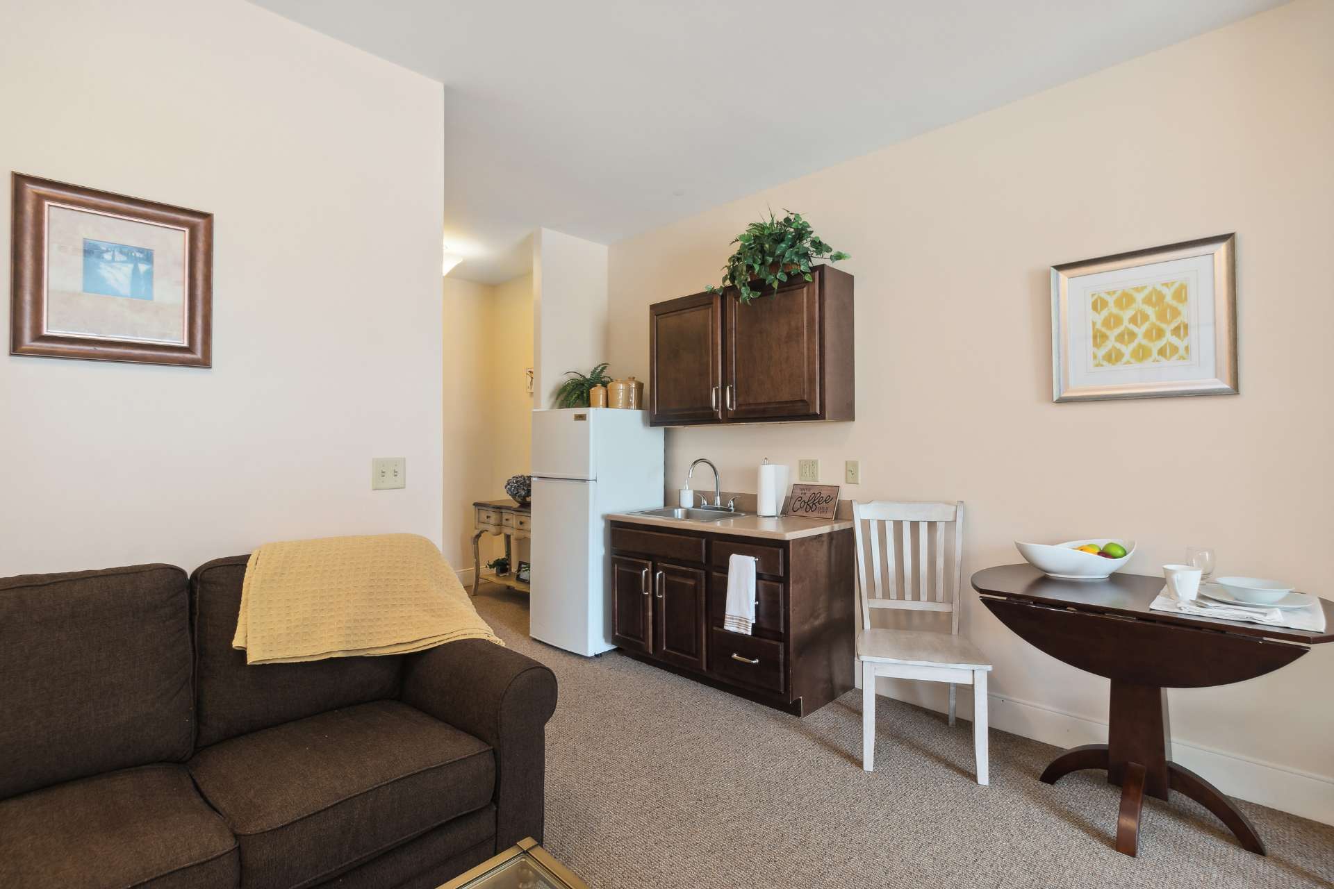 A private fridge and kitchen sink, with a small table and sofa.