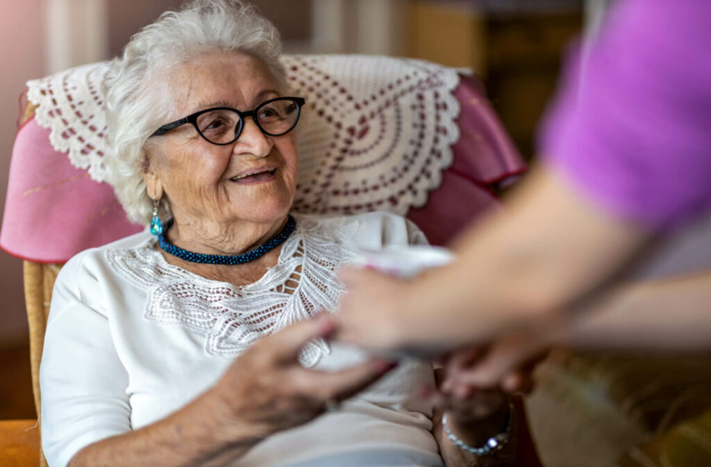 a woman in memory care holds the hands of a carer