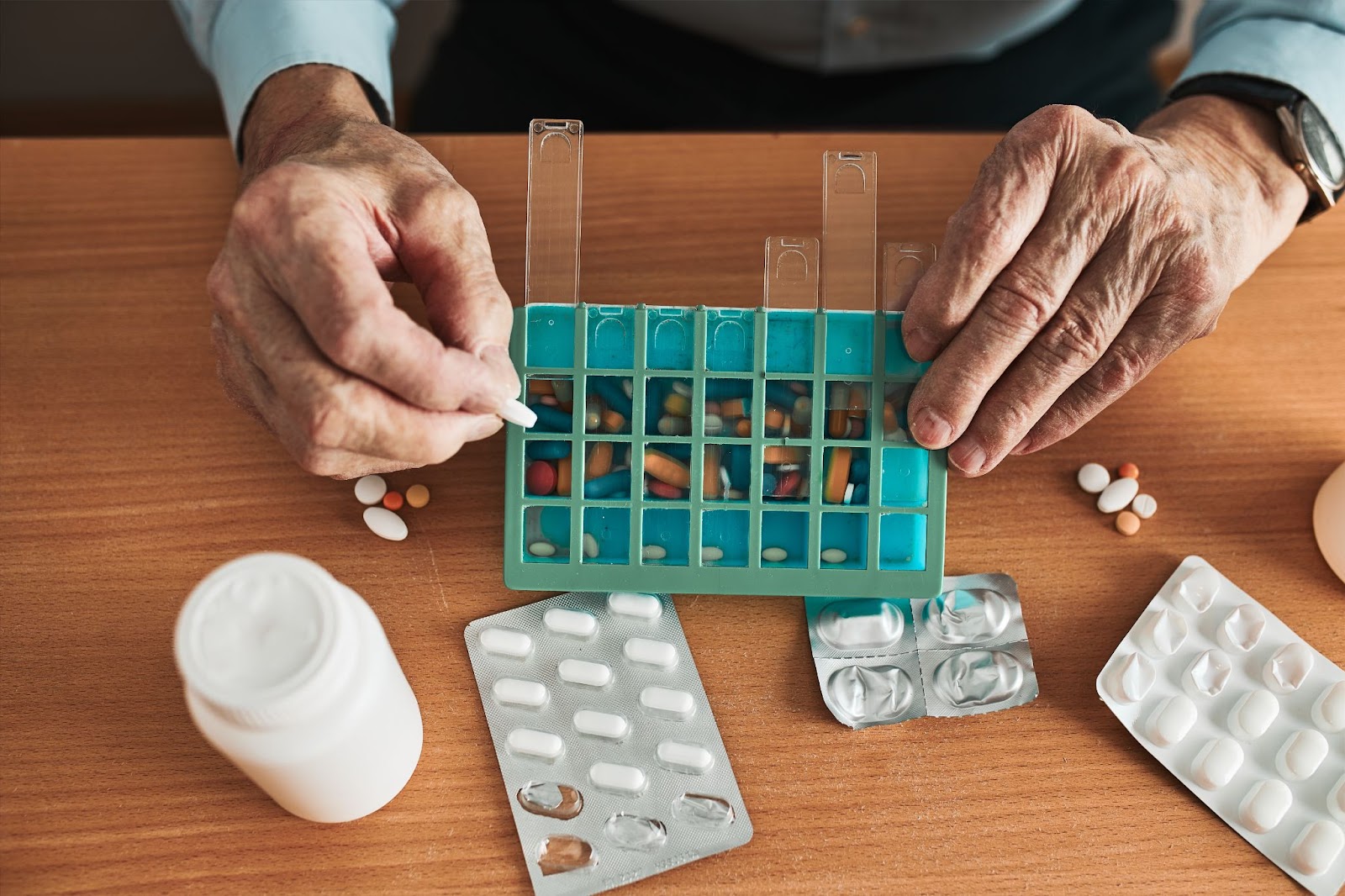 A close-up image of a senior sorting medications in a pill box.