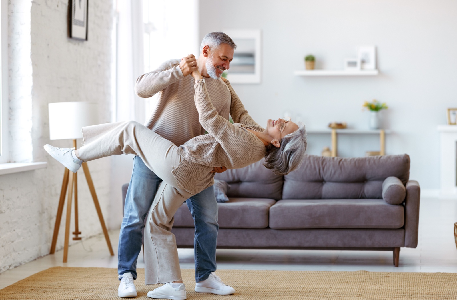 A happy senior couple dance together in their new senior apartment.