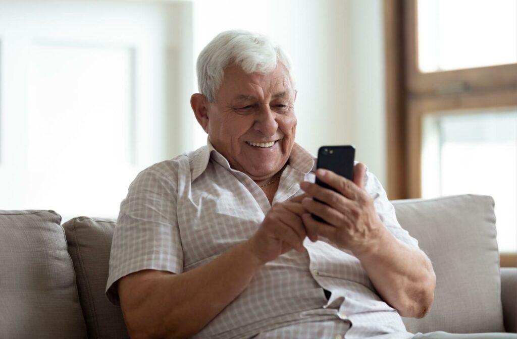 A smiling senior uses technology to aid in their communication with their loved ones regardless of speaking trouble.