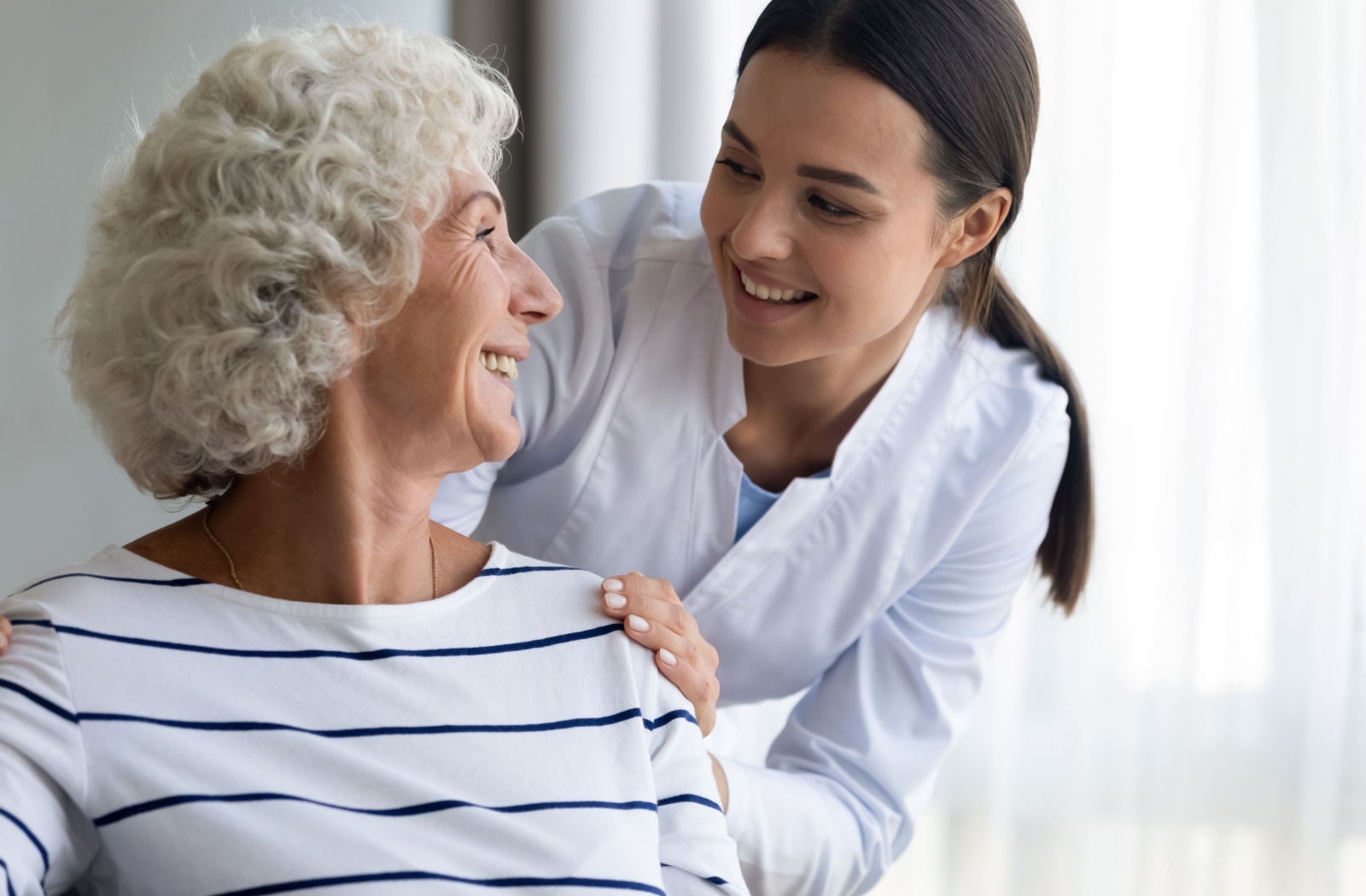 A caregiver checking on a smiling new resident in a respite care community.