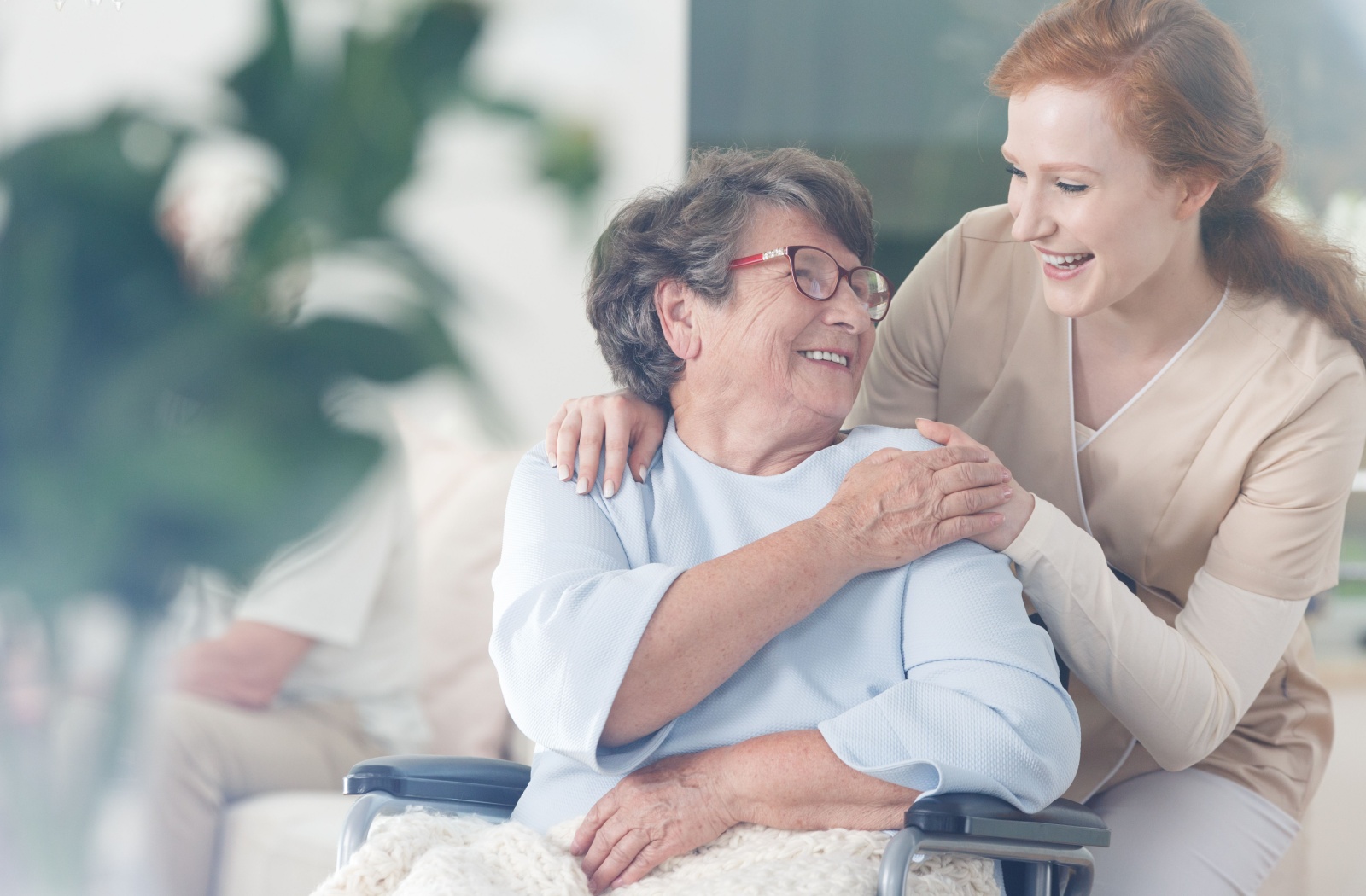 A caregiver and a resident in respite care laughing while touring a common area.